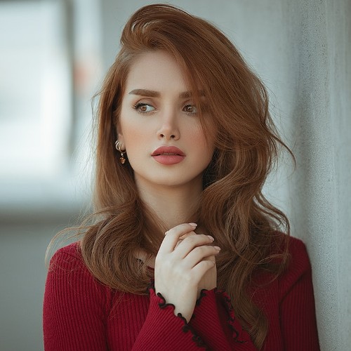 Portrait of a woman with auburn haira and golden eyes, bearing an expression of what might me concern.